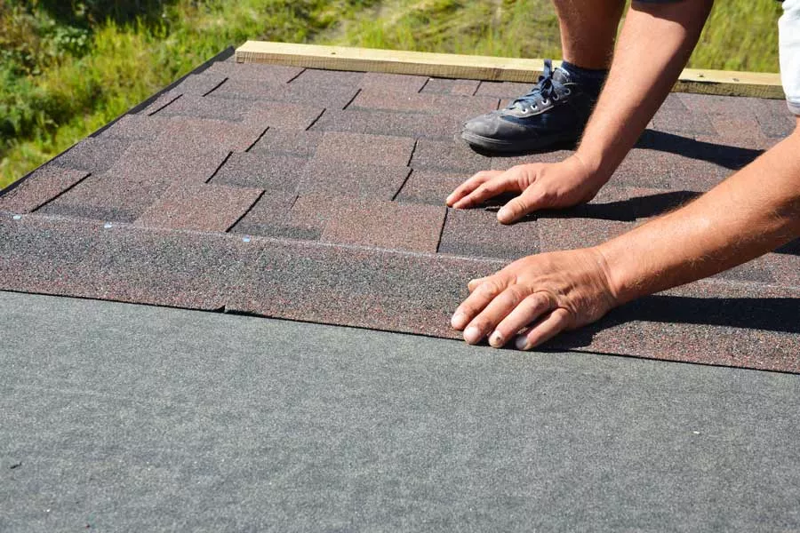 Roofer installing shingles on top of roof underlayment