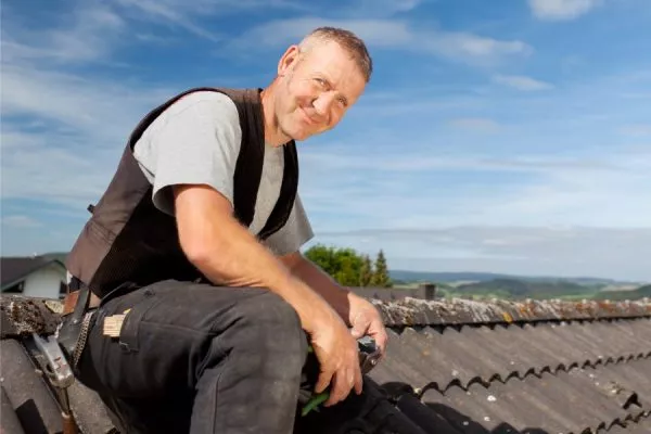 San Marcos Roofer smiling sitting on the roof.