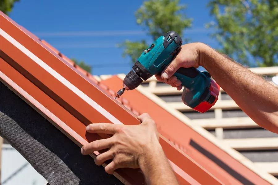 person drilling panels into a metal roof