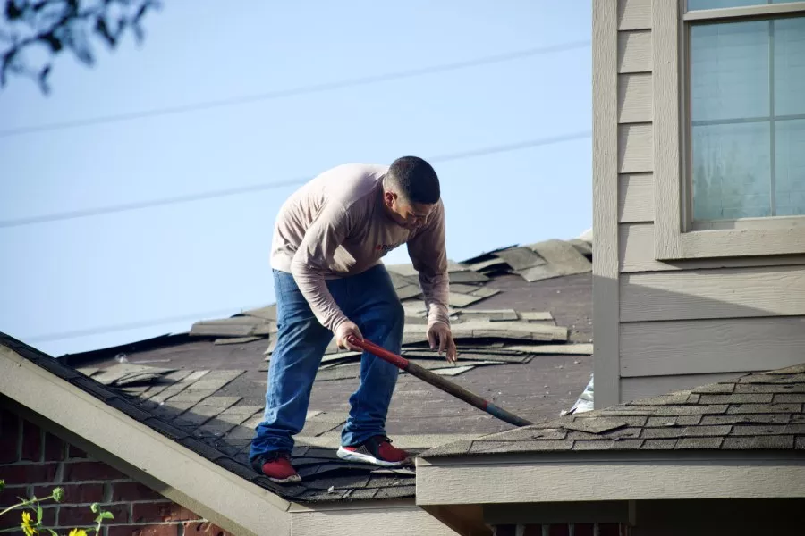 Professional San Marcos roofer working diligently to replace shingles