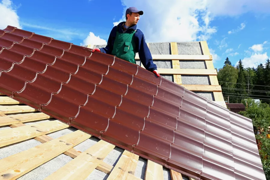 A worker installs a Buda metal roof on a sunny day with clear skies.