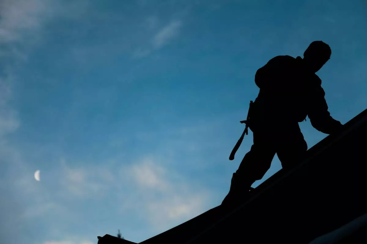 A silhouette of a New Braunfels Roofers team member working at dusk.
