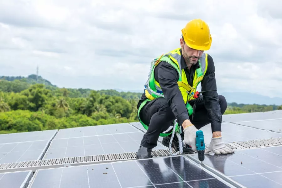 A worker installing solar panels during a project for commercial roofing in Austin.