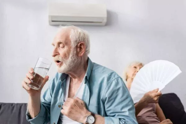 A man drinking water and a woman with fan that could benefit from a Buda solar installation to keep cool and save money.