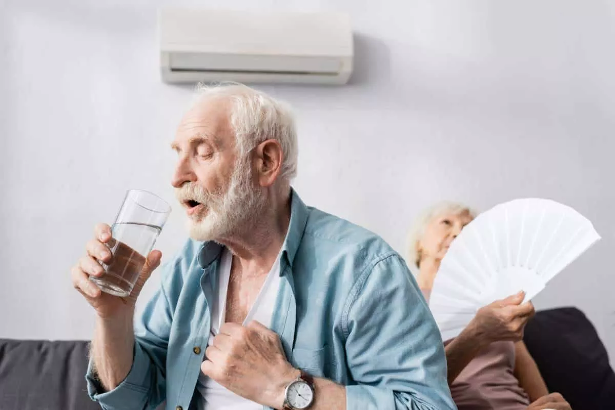 A man drinking water and a woman with fan that could benefit from a Buda solar installation to keep cool and save money.