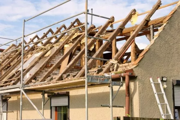Wimberley roofers repairing a home's damaged roof with scaffolding setup.