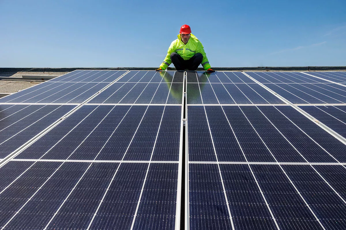A roofer inspects Austin commercial solar panels on a sunny day.
