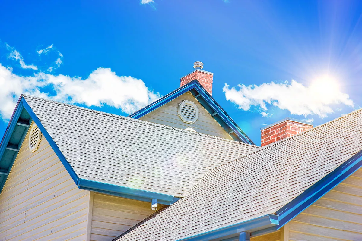 A sunlit roof in Austin with blue sky and fluffy clouds in the background.