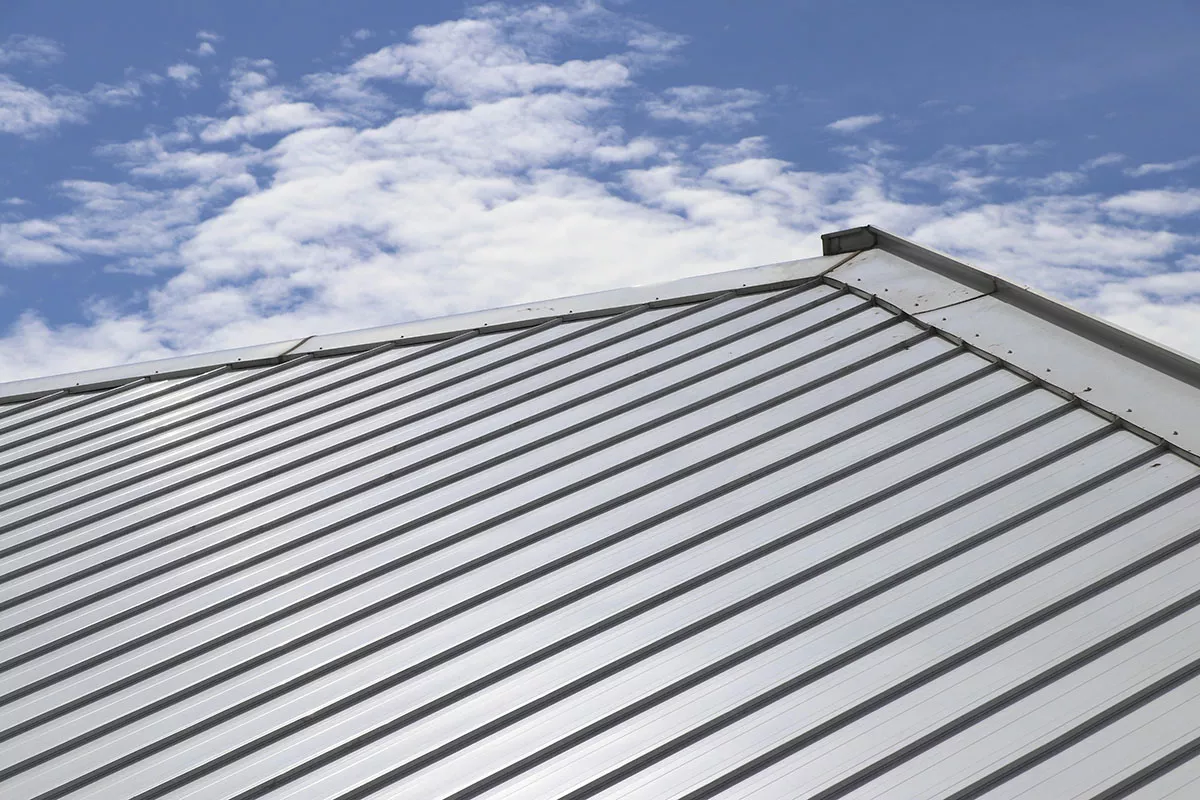 A light colored metal roof with a cool coating sits under a blue sky.