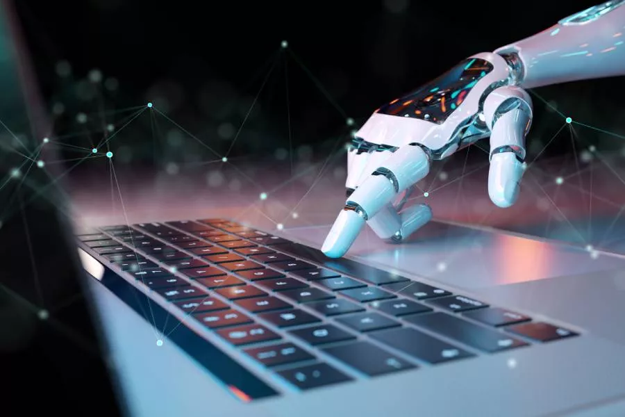 A robot hand controlling a laptop, signifying boosting San Marcos TX cybersecurity.