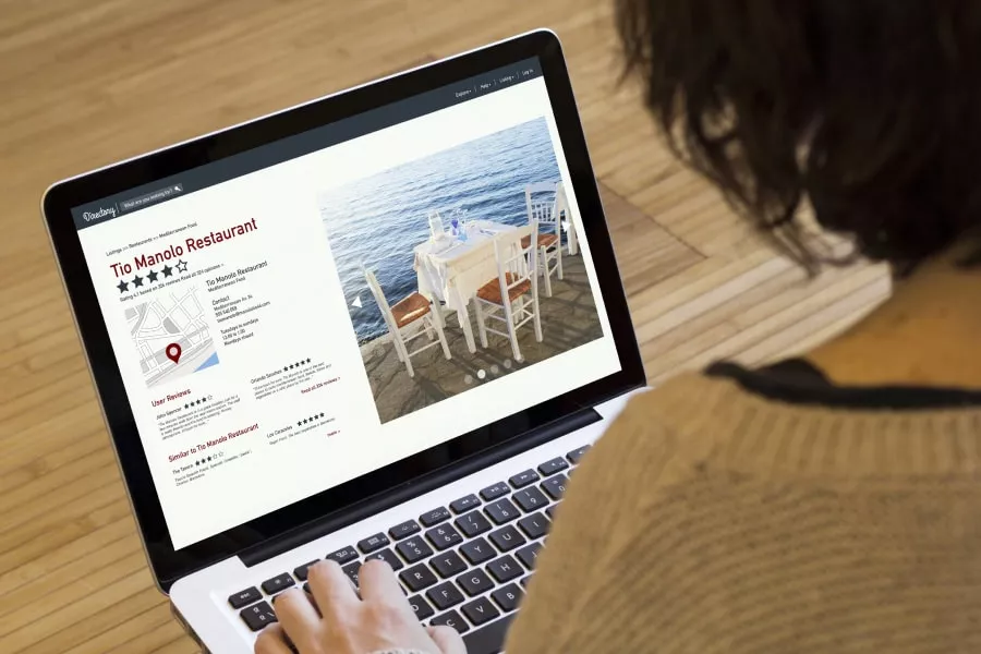 Person using laptop for Austin IT management research on a restaurant website.