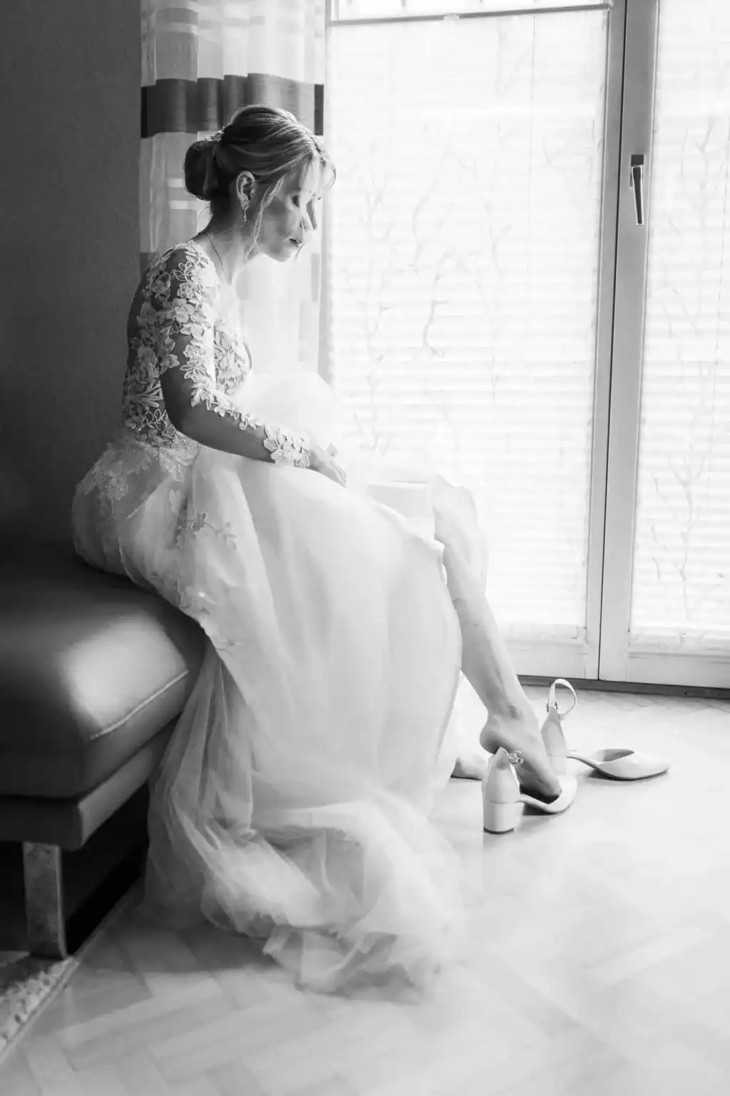 Braut zieht ihre Hochzeitsschuhe an, festgehalten in einem Schwarzweißmoment