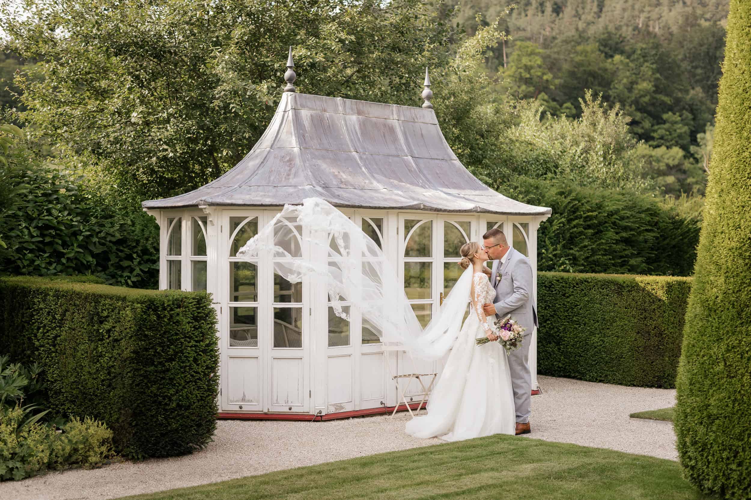 Romantisches Brautpaar vor Pavillon bei Hochzeit im Grünen.