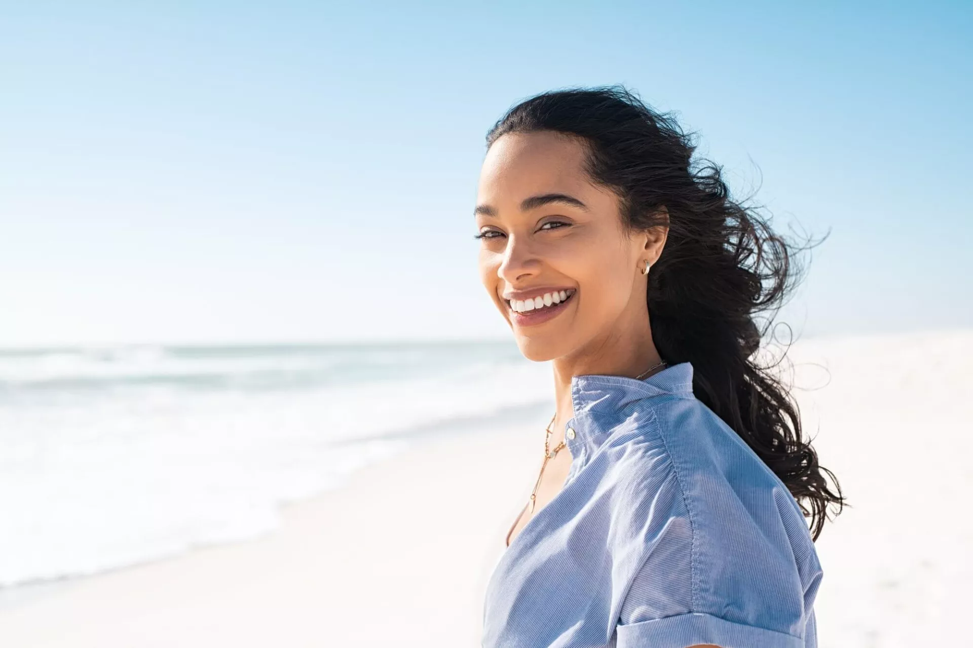 Smiling woman on a beach, representing emotional healing and recovery from trauma.