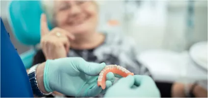 Dentist with surgical gloves holding dentures