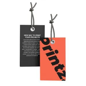 Two rectangular tags with rounded corners hanging by gray strings. The tag on the left is black with white text detailing a printing service. The tag on the right is orange with diagonal, bold black text reading "Printz.
