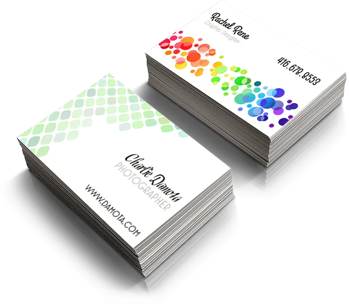 Two stacks of business cards. The left stack features a green gradient hexagonal pattern with the text "Charlie Dambis, Photographer, www.dambis.com". The right stack has multicolored circular patterns with the text "Rachel Rene, Graphic Designer, 416-678-8553".