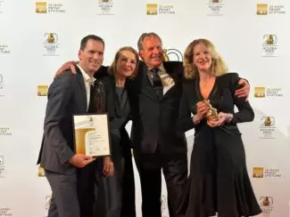 Products and Features leadership team of four people standing in front of a banner to celebrate winning the 2025 Houska Prize