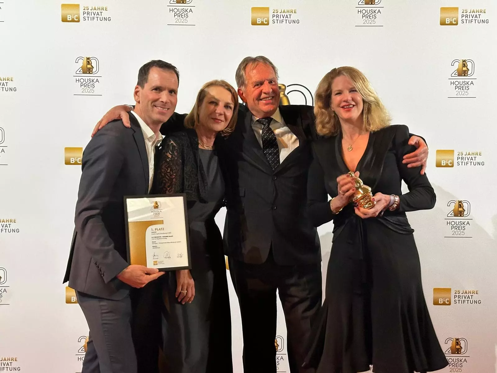 Products and Features leadership team of four people standing in front of a banner to celebrate winning the 2025 Houska Prize