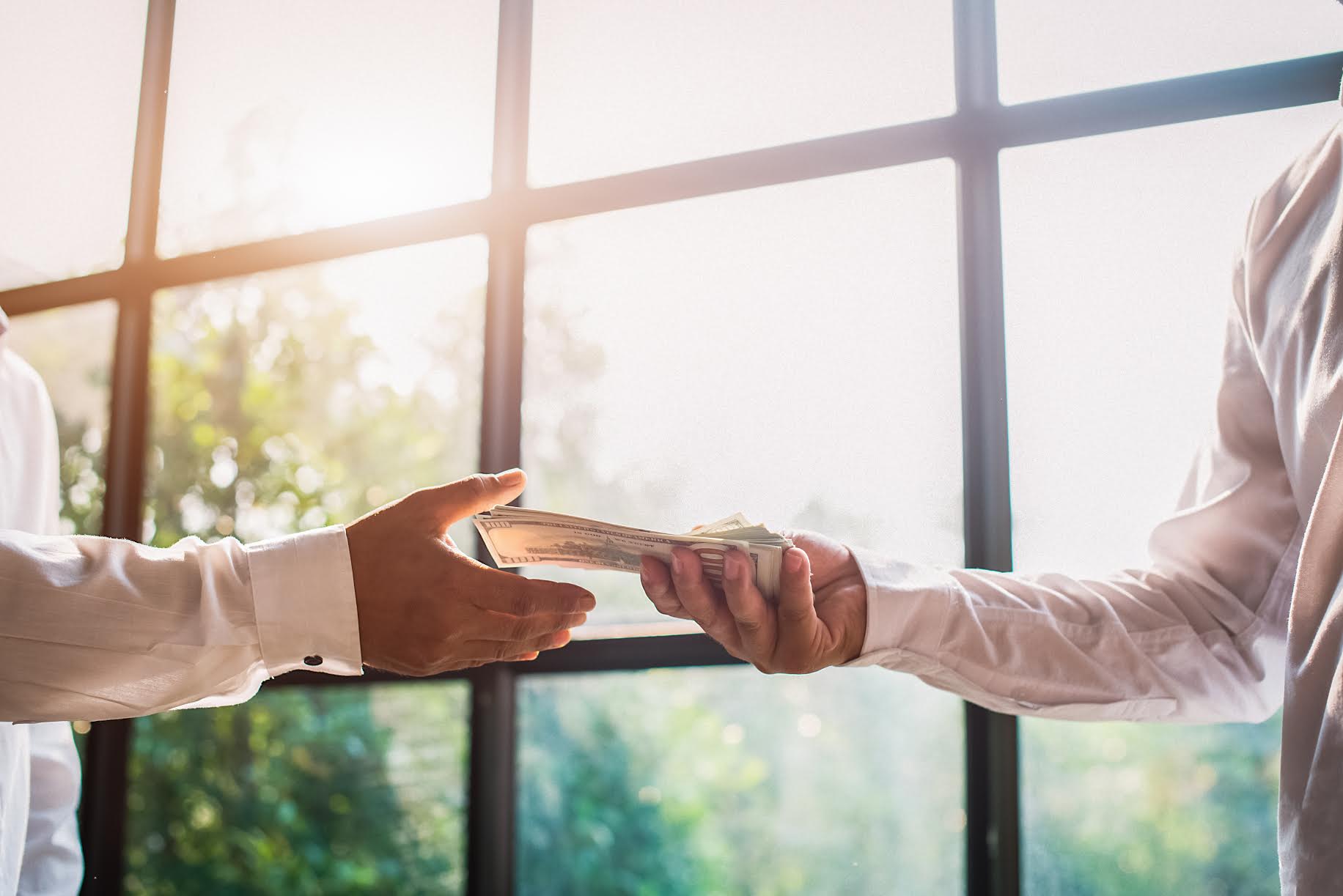 Hand receiving money, US dollars, from business man in office – Image