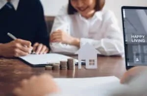 Couples signed a contract to buy a house from the broker. Coin to stack money and model house placed on the table, financial Business Growth.