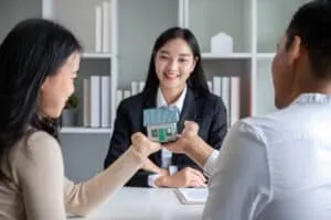 The real estate agent makes an offer to get the couple to sign a contract to buy the house. Happy male and female married customers make intimate deals with agents. real estate concept.