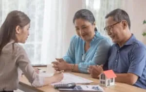 Elderly couples satisfying service in purchasing retirement residence. A detailed contract with saleswoman ensures a smooth transition, including key handovers after agreement on terms and conditions