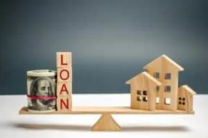 Miniature wooden house, dollars and the inscription Loan on the scales. Buying a home in debt. Family investment in real estate and risk management concept. Loan for a mortgage. apartment rental sale
