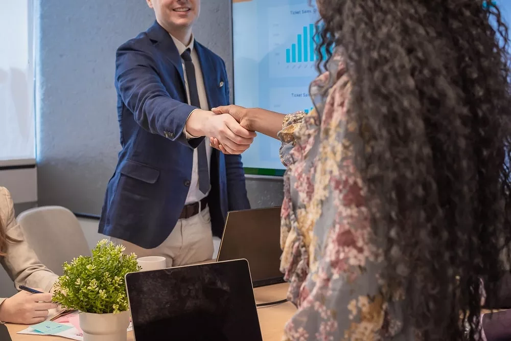 Business man shake hands with business women agreeing on partnerships or introducing themselves for first time meet.