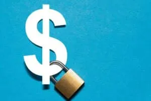 Padlock attached to a white dollar sign on the blue background. Safety and insurance concept.