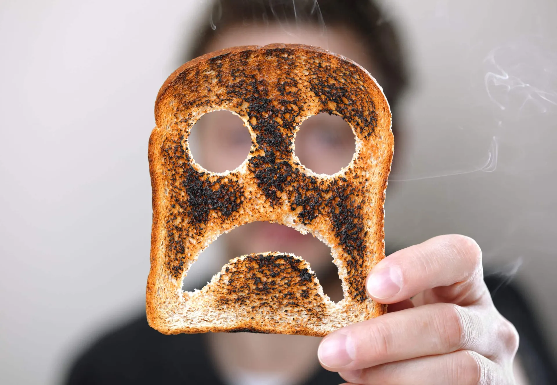 Ein Mann hält ein Stück Toast mit einem traurigen Gesicht hoch und drückt damit seine Gesundheit aus.