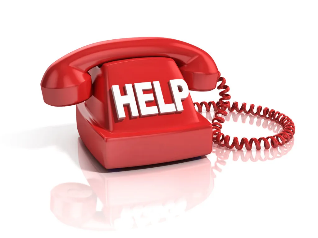 Ein rotes Wählscheibentelefon mit dem Wort "HELP" in großen weißen Buchstaben anstelle der Wählscheibe symbolisiert die systemische beratung; das aufgewickelte Kabel des Telefons ist vor einem weißen Hintergrund zu sehen.