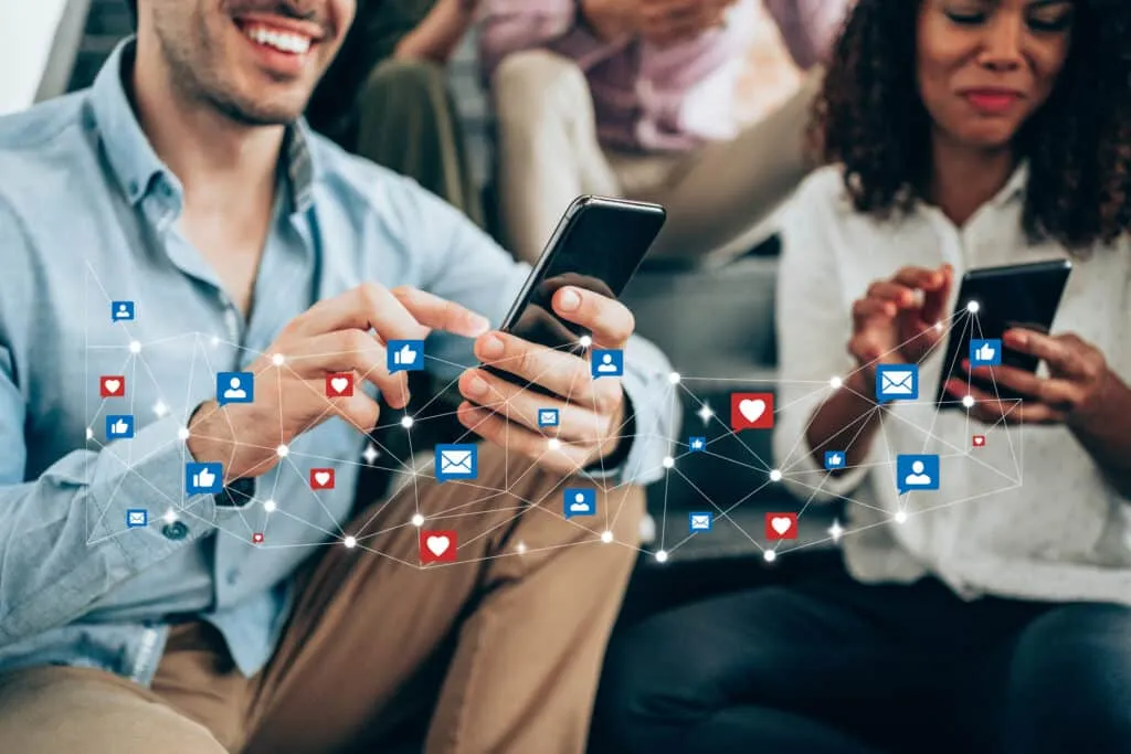 Multi-ethnic group of young people sitting on stairs and using smartphones. Young smiling man receives notifications on smart phone. Social media and digital online concept. Social media and people network technology concept.