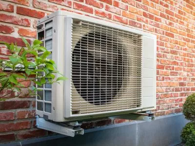 Air conditioning heat pump outdoor unit against brick wall. Air conditioning heat pump outdoor unit against brick wall.