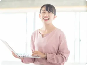 PCを持ってはち切れんばかりの笑顔を見せる女性