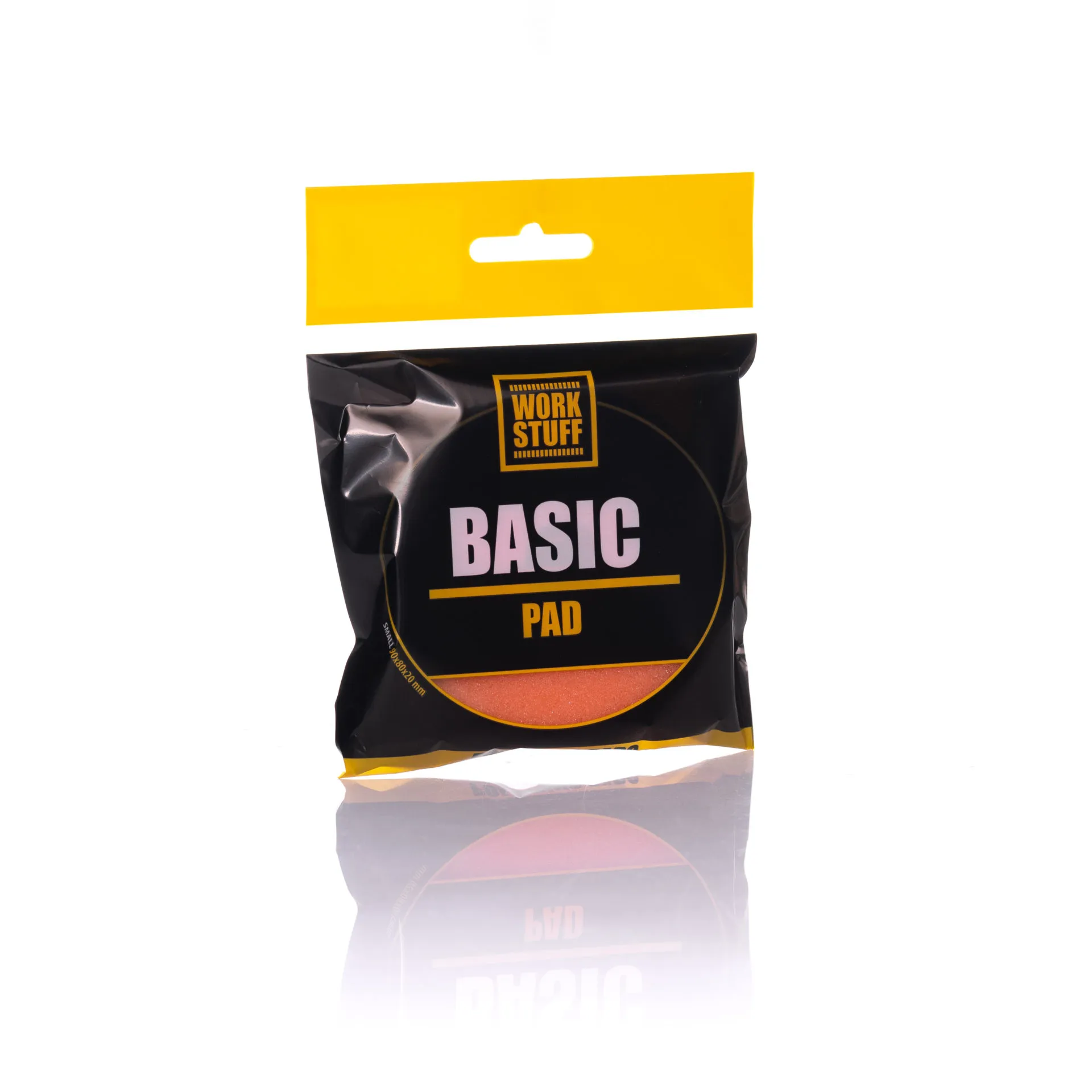 Czarno-żółte opakowanie Work Stuff BASIC PAD stoi pionowo, pokazując okrągłą pomarańczową podkładkę wewnątrz i jej odbicie poniżej.