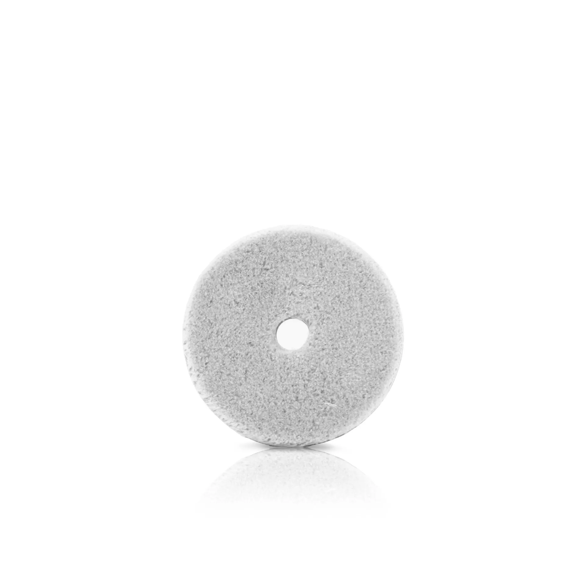 A round, flat gray pumice stone with a small hole in the center, resting on a white background with a faint reflection.