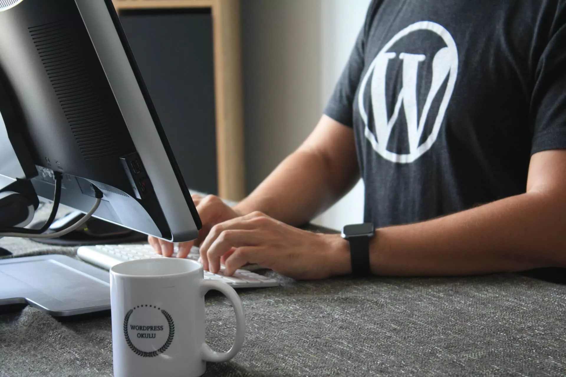 A man typing on a computer with the Wordpress logo.