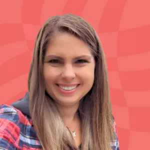 Smiling person with long brown hair wearing a plaid shirt poses against a red textured background.