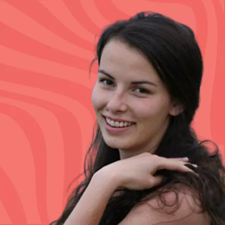 Smiling person with long dark hair against a wavy coral background, resting their chin on their hand.