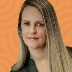 A person with long blonde hair is posed against an orange background with circular patterns. They are wearing a green top and are looking directly at the camera with a slight smile.