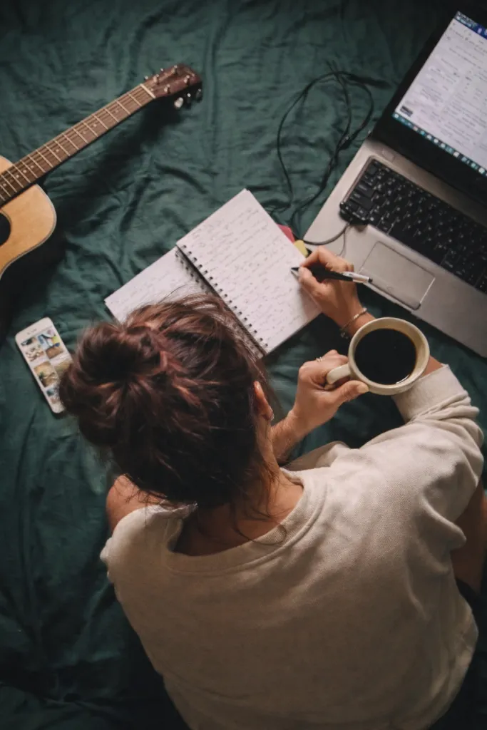 Woman journaling, coffee, guitar, computer
