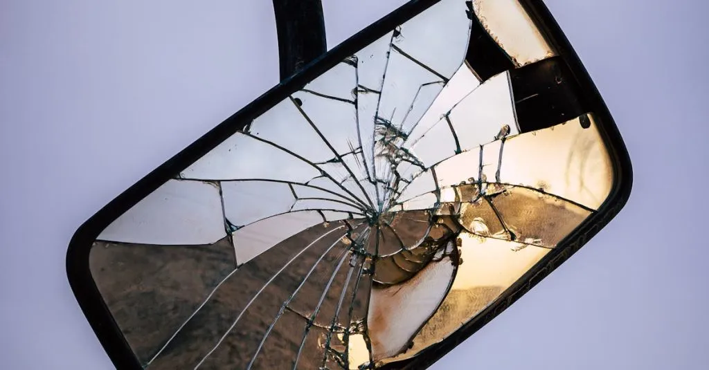 A close-up of a cracked side mirror reflecting surroundings.