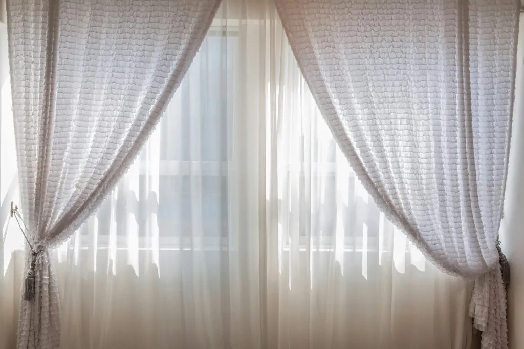 Sun shining through elegant white curtains in a cozy, modern interior setting.