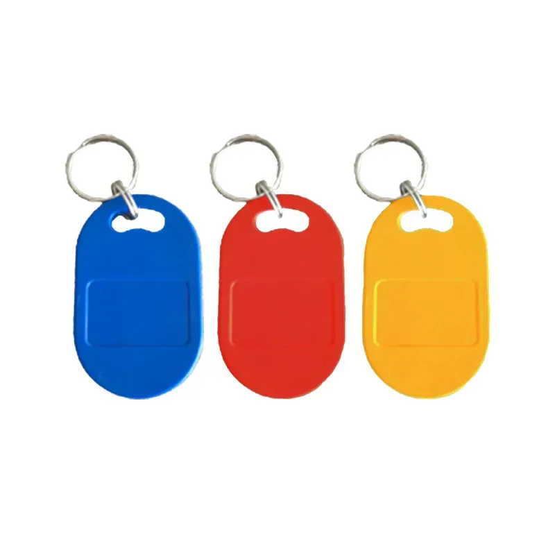 तीन mifare keyfobs (1) निळ्या रंगात, लाल, आणि पिवळा, प्रत्येकाला अंडाकृती आकार आणि मेटल की रिंग जोडलेली आहे.