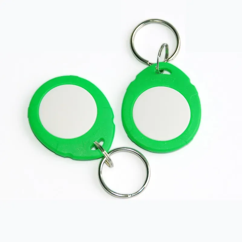 Dalawang berdeng plastik na Multi RFID Keyfobs (1) na may mga pabilog na metal na sentro at nakakabit na mga key ring sa puting background.