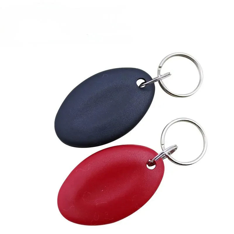 An eochair rfid fob a chóipeáil (1) sraith táirgí, lena n-áirítear dhá fhób eochrach ubhchruthach - ceann dubh agus ceann dearg - feistithe le clibeanna RFID agus ceangailte le fáinne eochair airgid, ar taispeáint i gcoinne cúlra plain bán.