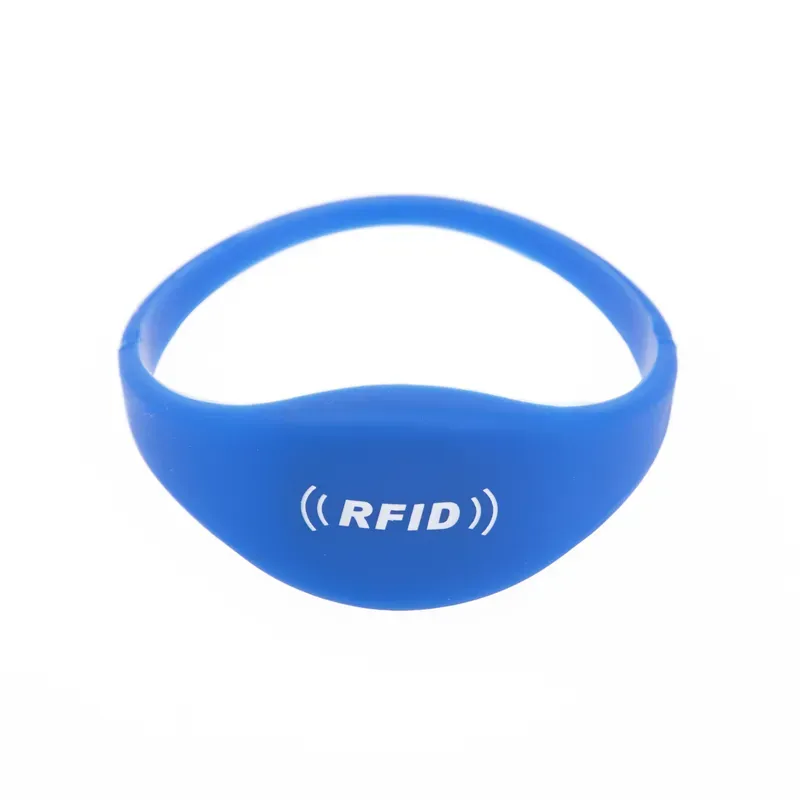 สร้อยข้อมือแท็ก RFID สีน้ำเงินประดับด้วยโลโก้ RFID สีขาวและไอคอนสัญญาณที่ด้านหน้า, ตั้งค่ากับพื้นหลังสีขาว. อุปกรณ์เสริมที่สง่างามนี้รวมเข้าด้วยกันอย่างราบรื่นกับกำไลแท็ก RFID อื่น ๆ, เสนอทั้งสไตล์และความปลอดภัย.