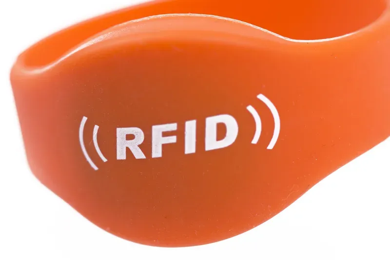 Izbliza narančastih RFID narukvica za događaje, featuring the text "RFID" s signalnim linijama s obje strane.