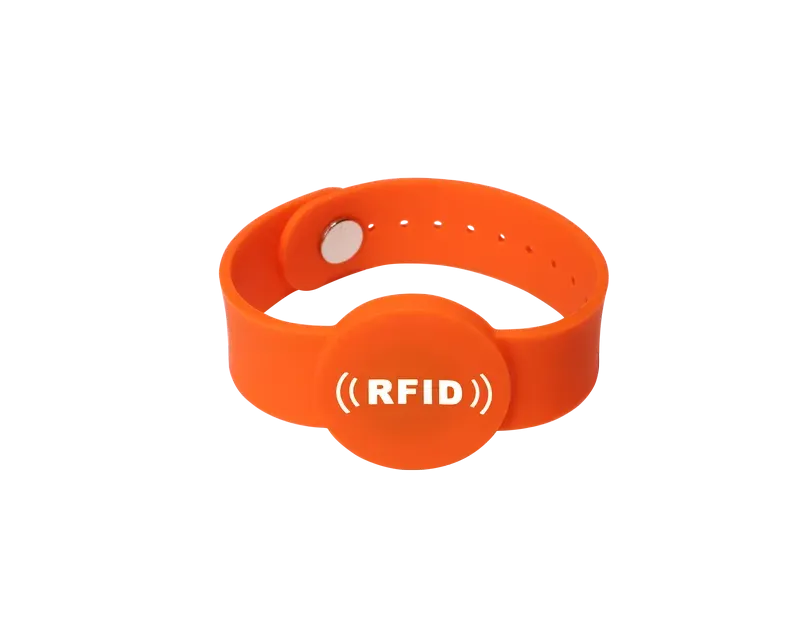 A vibrant orange RFID wristband featuring a circular central section showcasing "RFID" baltā tekstā, Lieliski piemērots RFID aproces risinājumiem.